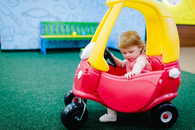 glückliche Kinder kleines Mädchen fährt auf einem roten großen Auto auf der Straße hautnah das Baby fährt Auto baby