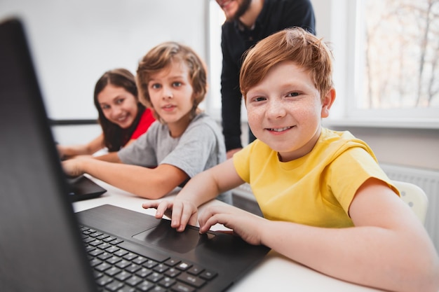 Glückliche Kinder lernen mit Laptops im Klassenzimmer