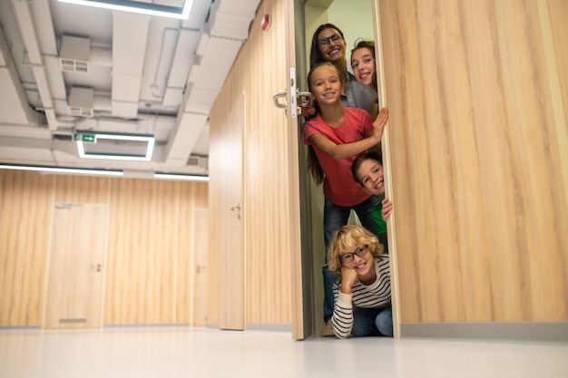 Glückliche Kinder mit einer Frau, die die Tür öffnet und in die Kamera schaut