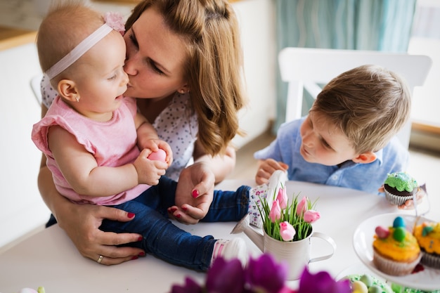 Glückliche Kinder mit Mutter, die Cupcakes in der Osterszene isst