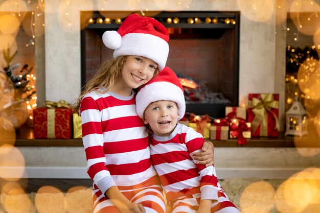 Glückliche Kinder nahe Kamin zu Weihnachten. Kinder haben Spaß zu Hause.