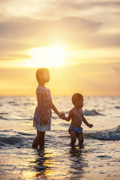 Glückliche Kinder spielen am Strand. Konzept der glücklichen freundlichen Schwester und des Bruders.