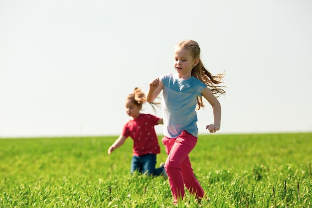 Glückliche Kinder von Jungen und Mädchen laufen an einem sonnigen Sommertag im Park auf dem Gras