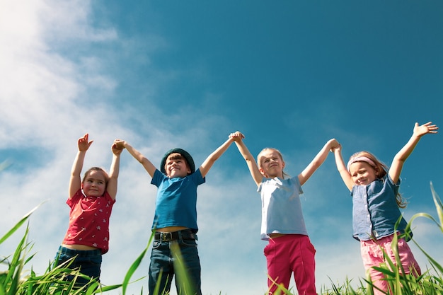 Glückliche Kinder von Jungen und Mädchen laufen an einem sonnigen Sommertag im Park auf dem Gras