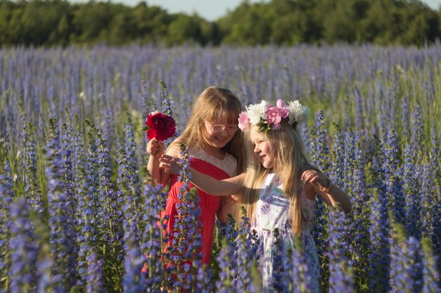 Glückliche Kindermädchen mit Blumen in der Sommerwiese in der Natur. Mädchen in Kränzen. Lächelnde Kinder.