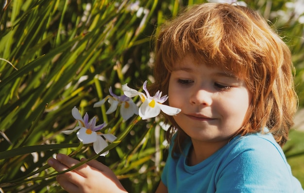Glückliche Kindheit Frühlingskindallergie schnüffelt blühende Blume Nettes Kind im Blütengarten