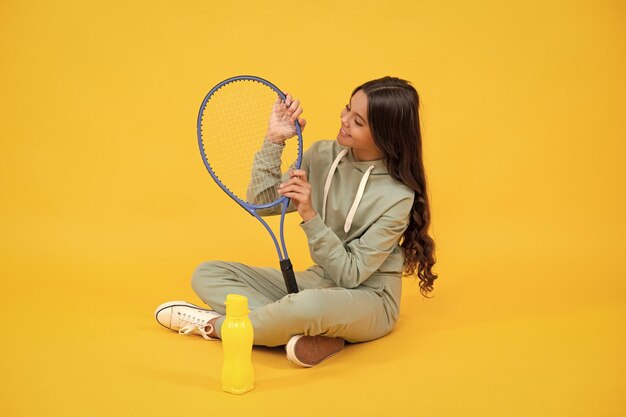 Glückliche Kindheit sein hydratisiertes Kind sitzt mit Schläger und Wasserflasche Kind mit Tennisschläger