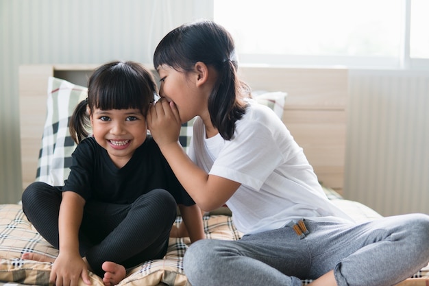 Glückliche kleine asiatische Geschwister, die Geheimnisse teilen