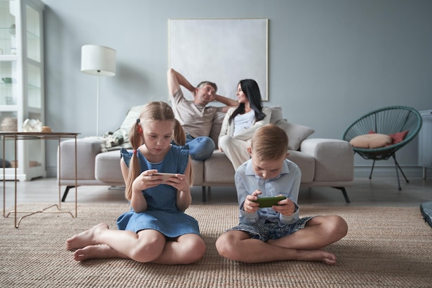 Glückliche kleine Kinder, Bruder und Schwester, benutzen zu Hause Telefone