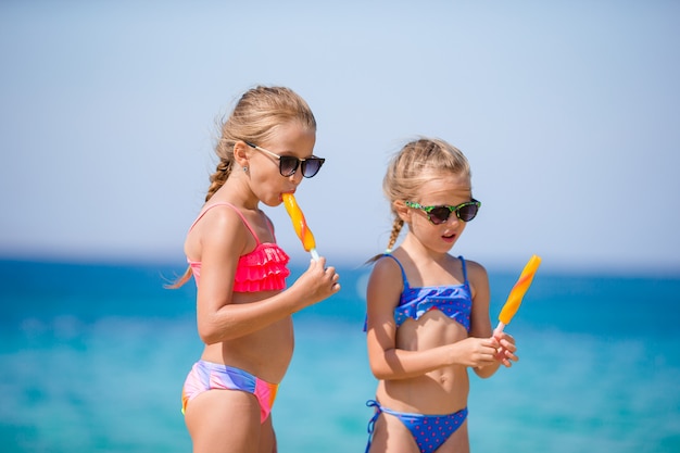 Glückliche kleine Mädchen, die Eiscreme während der Strandferien essen