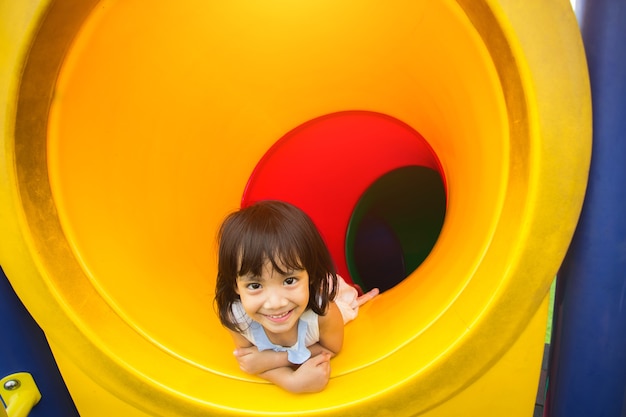 glückliche kleine Mädchen, die Kamera im Tunnel auf Spielplatz betrachten.
