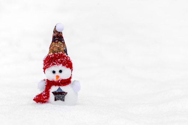 Glückliche kleine Schneemänner in roter blauer Mütze und Schal, die im Winterschneehintergrund stehen