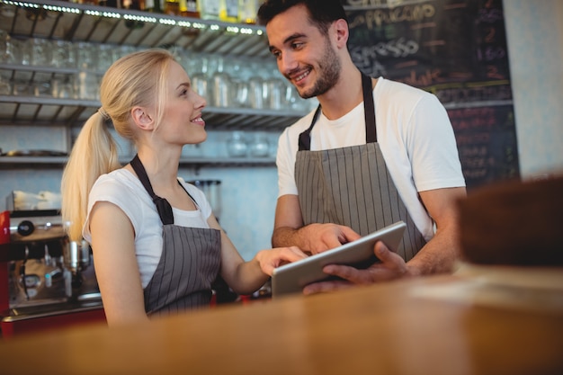 Glückliche Kollegen, die mit digitaler Tablette sich besprechen