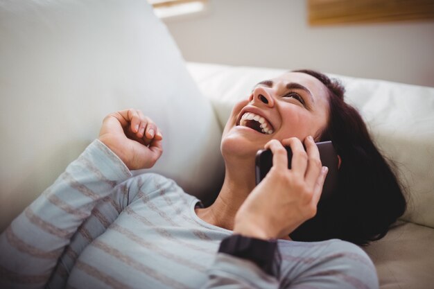 Glückliche lachende Frau bei der Unterhaltung am Telefon