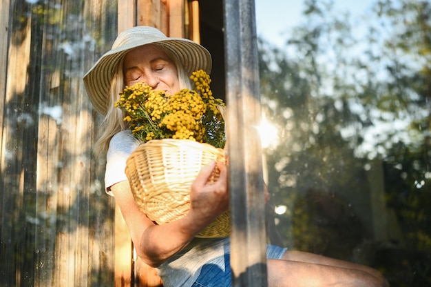 Glückliche lächelnde ältere Frau, die mit Blumen aufwirft