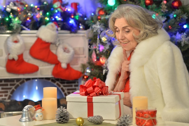 Glückliche lächelnde ältere Frau mit Geschenk zu Weihnachten