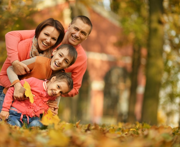 Glückliche lächelnde Familie, die im Herbstpark sich entspannt