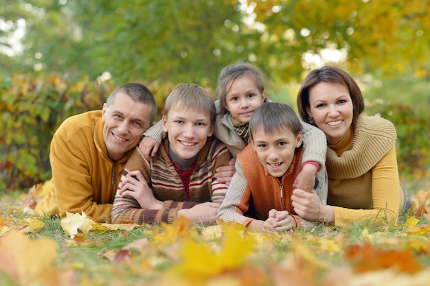 Glückliche lächelnde Familie, die im Herbstpark sich entspannt