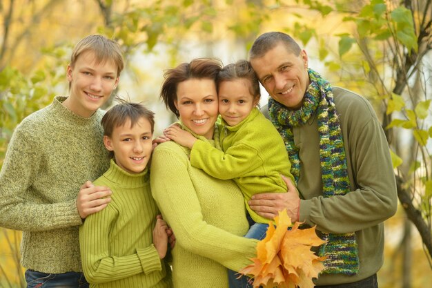 Glückliche lächelnde Familie, die im Herbstpark sich entspannt