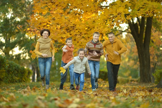 Glückliche lächelnde Familie, die im Herbstpark sich entspannt