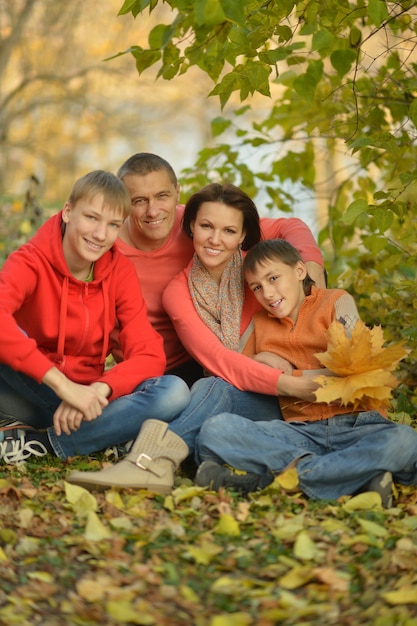 Glückliche lächelnde Familie, die im Herbstpark sich entspannt