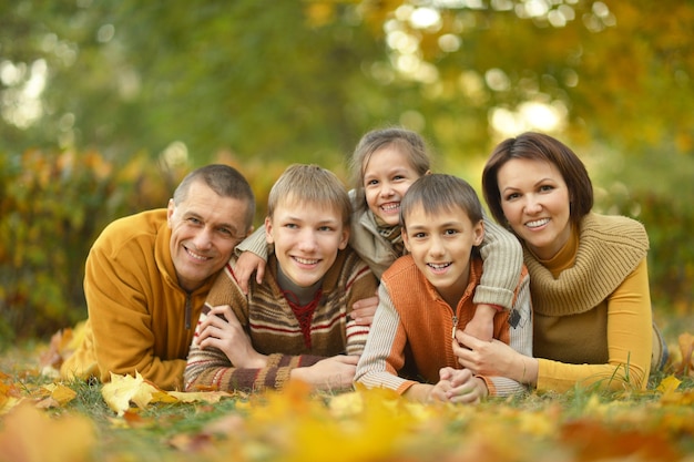 Glückliche lächelnde Familie, die im Herbstwald sich entspannt