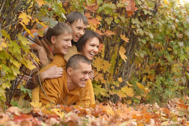 Glückliche lächelnde Familie, die im Herbstwald sich entspannt