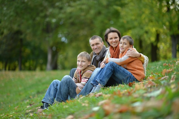 Glückliche lächelnde Familie im Herbstwaldsitzen