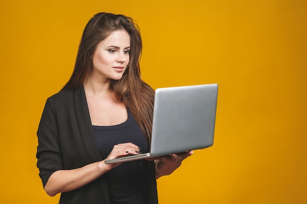 Glückliche lächelnde Frau des jungen Geschäfts, die Laptop hält und E-Mail an ihren besten Freund sendet.