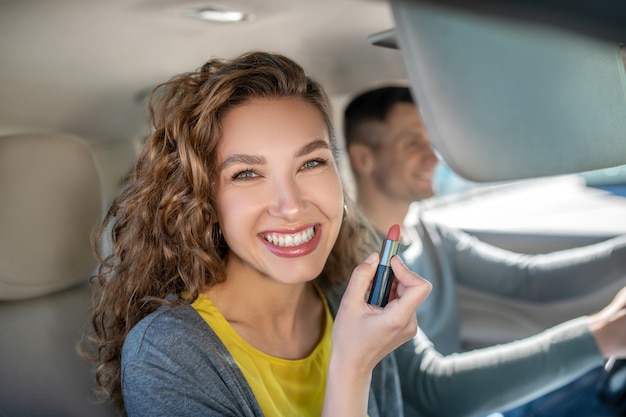 Glückliche lächelnde Frau mit Lippenstift im Auto