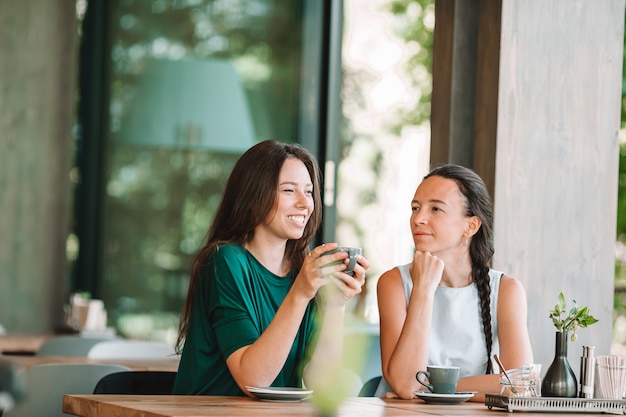 Glückliche lächelnde junge Frauen mit Kaffeetassen im Café.