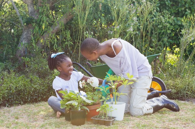 Glückliche lächelnde Mutter, die mit ihrer Tochter im Garten arbeitet