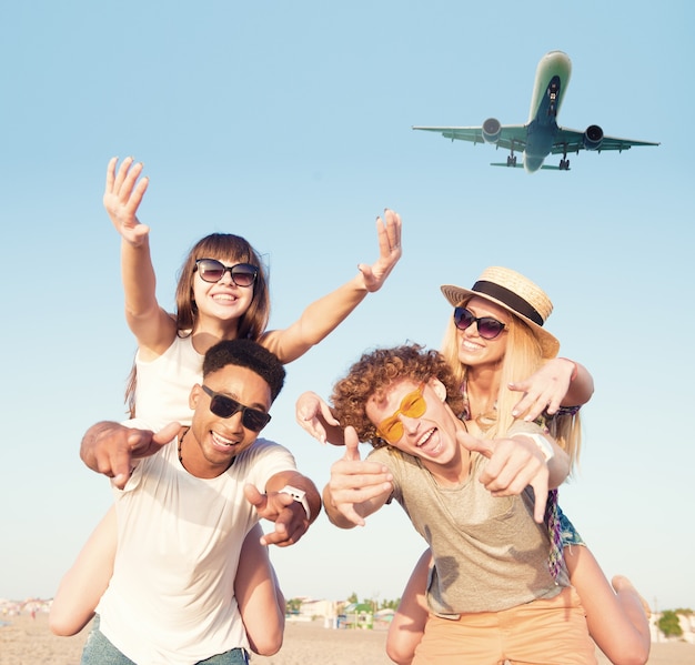 Glückliche lächelnde Paare, die am Strand mit Flugzeugen am Himmel spielen