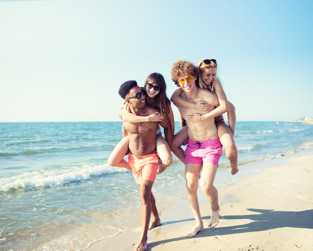 Glückliche lächelnde Paare, die am Strand spielen