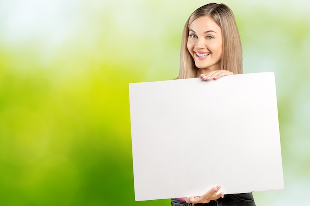 Foto glückliche lächelnde schöne junge frau in der rosa intelligenten freizeitbekleidung, die leeres schild zeigt