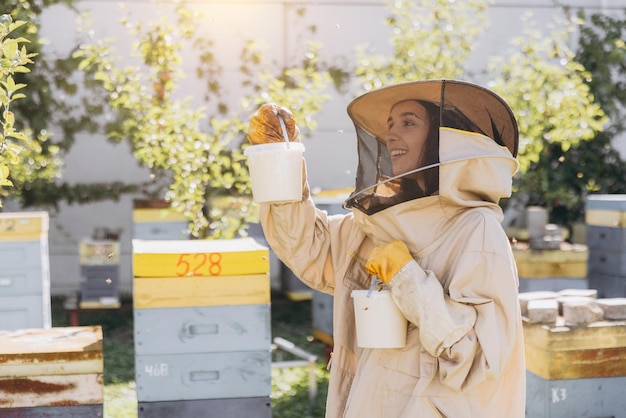 Glückliche lächelnde weibliche Imkerin hält bereit organischen Honig, der in einer Bienenfarm hergestellt wird