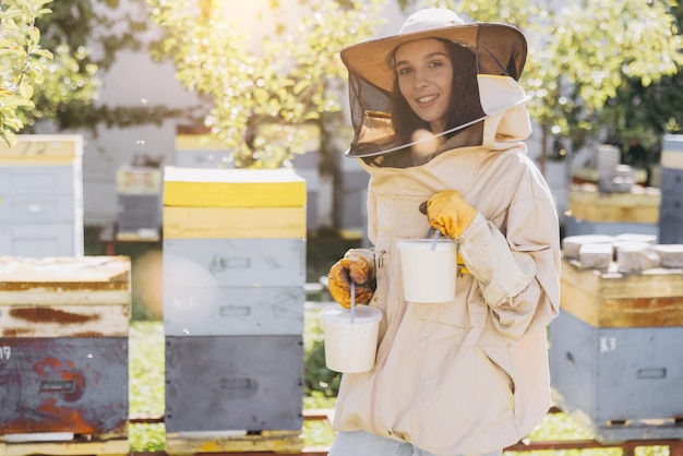 Glückliche lächelnde weibliche Imkerin hält bereit organischen Honig, der in einer Bienenfarm hergestellt wird