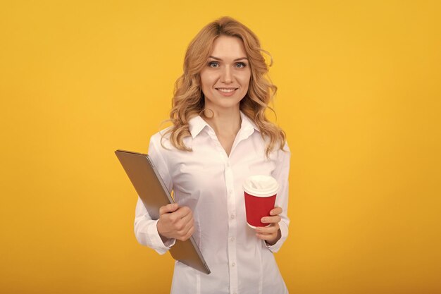 Glückliche Lehrerin mit Laptop zum Mitnehmen Pappbecher gelber Hintergrund Kaffeepause
