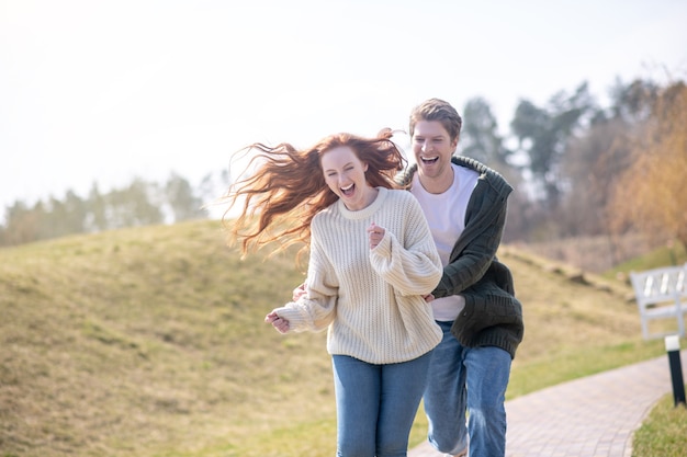 Glückliche Leute. Fröhliche lachende Frau mit Ingwer langen Haaren und attraktivem Mann, der sich an einem schönen Tag aktiv in der Natur ausruht