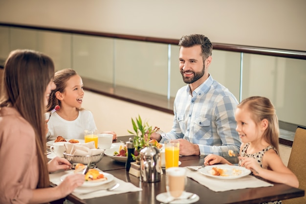 Glückliche Leute. Lächelnde Familie, die am Tisch sitzt und glücklich aussieht