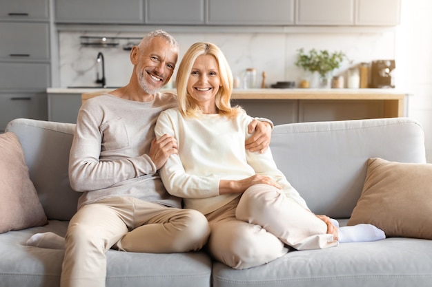 Glückliche, liebevolle ältere Ehepartner sitzen zu Hause auf der Couch