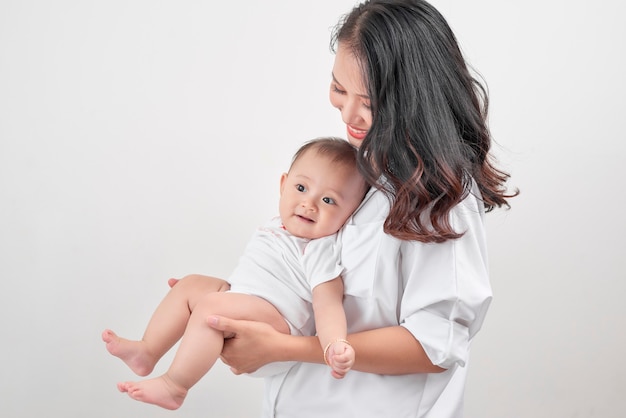 Glückliche liebevolle Familie. Junge lächelnde Mutter, die lachendes Baby umarmt.