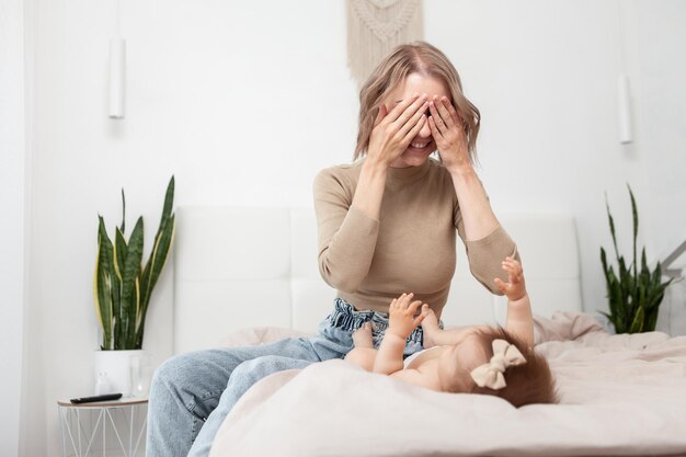 Glückliche, liebevolle Familie Junge Mutter spielt mit ihrem kleinen Mädchen im Schlafzimmer Mutter und Baby haben Spaß im Bett