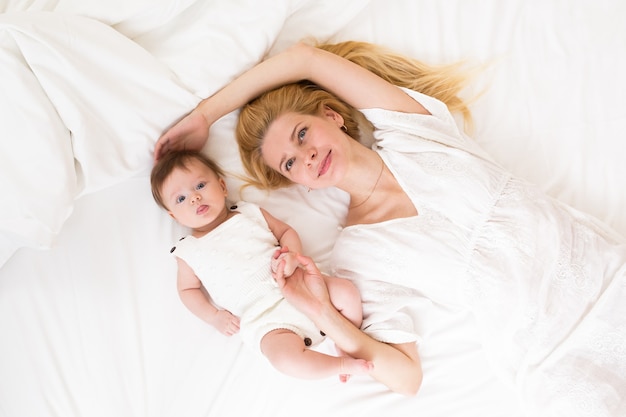 Glückliche liebevolle Familie. Mutter spielt mit ihrem Baby im Schlafzimmer, Ansicht von oben.