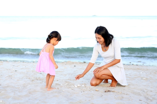 Glückliche liebevolle Familie. Mutter und ihr Tochterkindermädchen, die Sand am Strand spielen