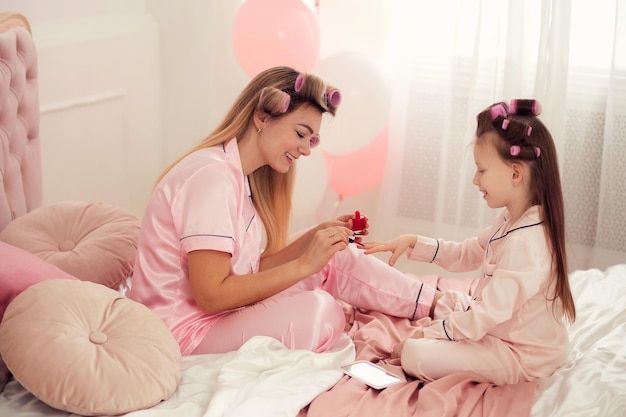 Glückliche liebevolle Familie Mutter und Tochter haben Spaß daran, im Schlafanzug auf dem Bett im Schlafzimmer zu sitzen