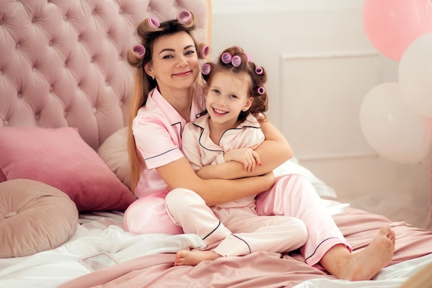 Foto glückliche liebevolle familie mutter und tochter haben spaß daran, im schlafanzug auf dem bett im schlafzimmer zu sitzen
