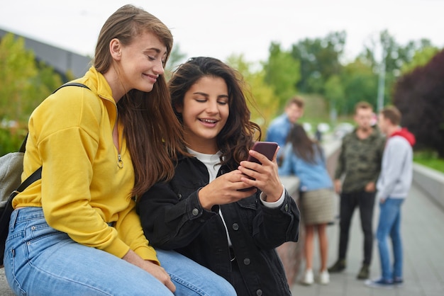 Glückliche Mädchen, die auf Smartphone schauen