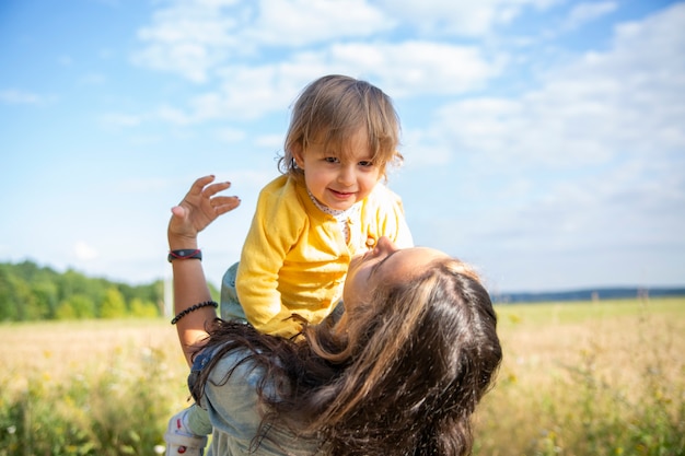 glückliche Mama und Baby spielen im Sommer an einem sonnigen Sommertag auf dem Feld