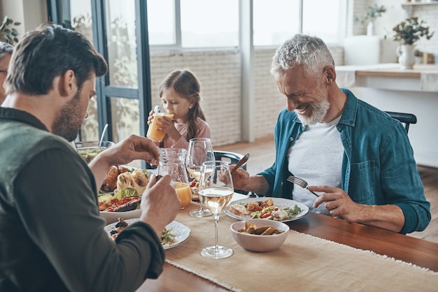 Glückliche Mehrgenerationenfamilie, die beim gemeinsamen Abendessen kommuniziert und lächelt smiling